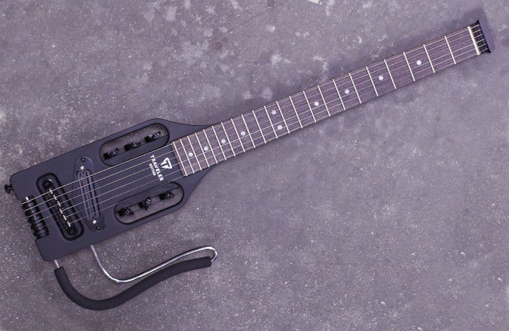 a black electric guitar lying on a grey surface